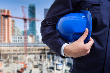 Mann auf Baustelle mit blauem Helm unter dem Arm